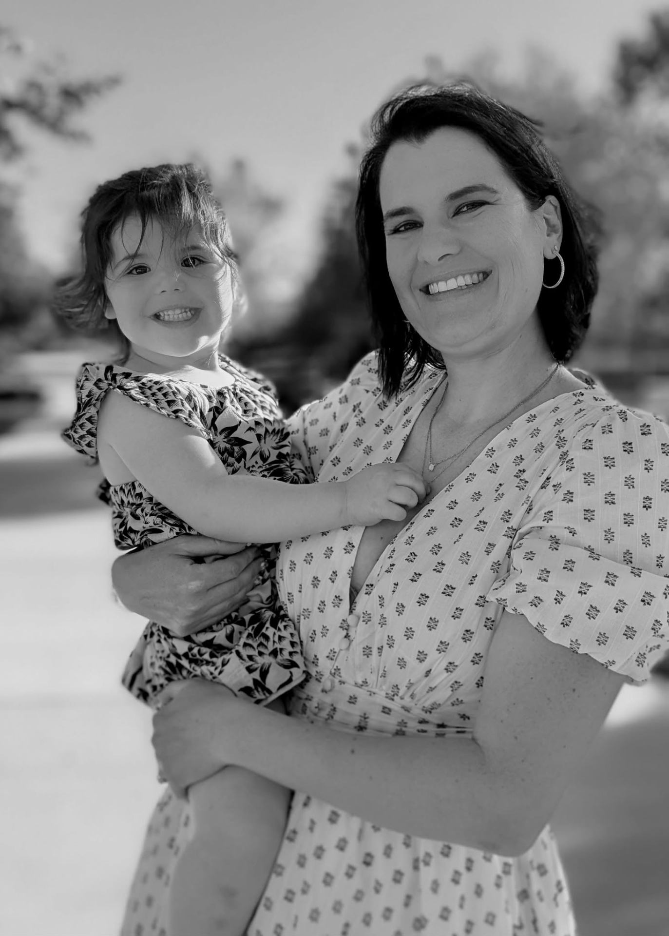Jessica Shaw holding daughter Lexi, both smiling, in a black-and-white portrait